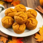 Golden gluten free pumpkin muffins on a plate, garnished with cinnamon sticks