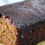 Gluten-free ginger cake loaf with powdered sugar, ginger, and spices on a rustic wooden board