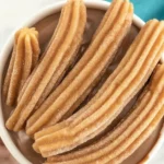 Homemade crispy gluten-free churros served with melted chocolate sauce.